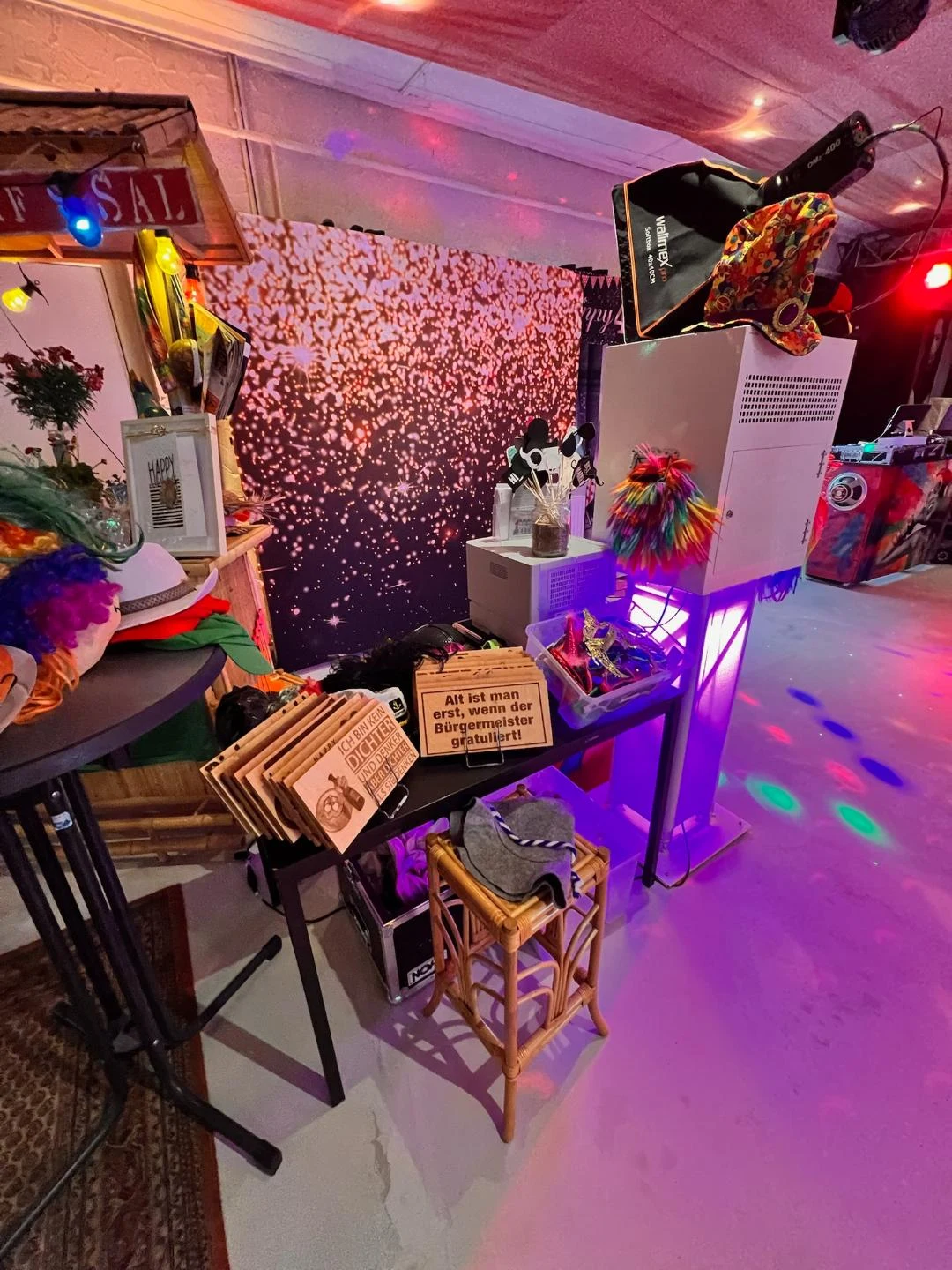 Schlitti’s Fotobox mit Beleuchtung, funkelndem Hintergrund und bunten Foto-Requisiten